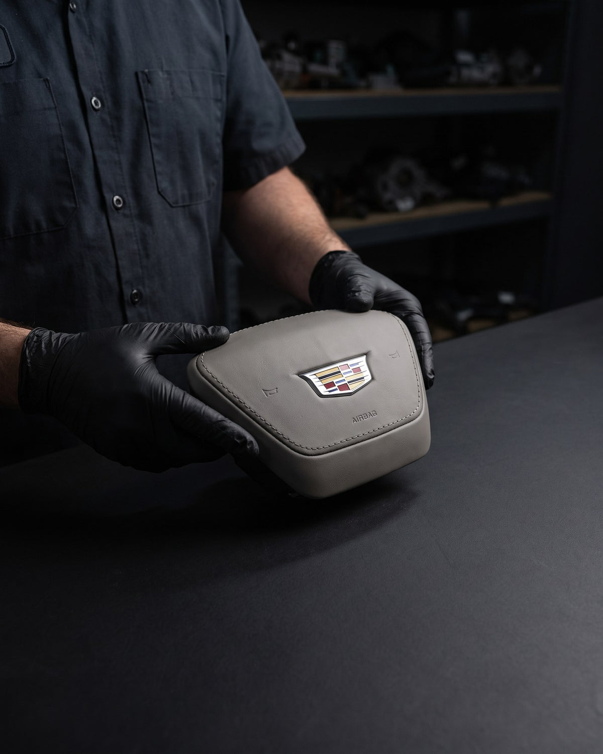 A technician in black gloves inspecting a genuine OEM steering wheel airbag
